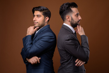 Studio shot of young handsome Iranian brothers together against 