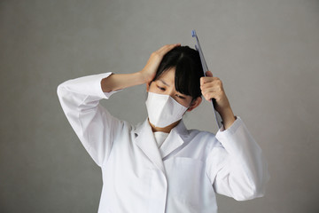 頭を抱える白衣の女性