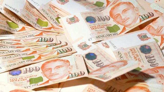 SGD hundred dollar bill scattered all around on a table