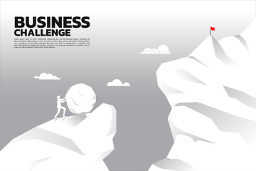 Silhouette of businessman pushing the big rock to the top of mountain with the abyss ahead. concept of business challenge and problem. © Panithan