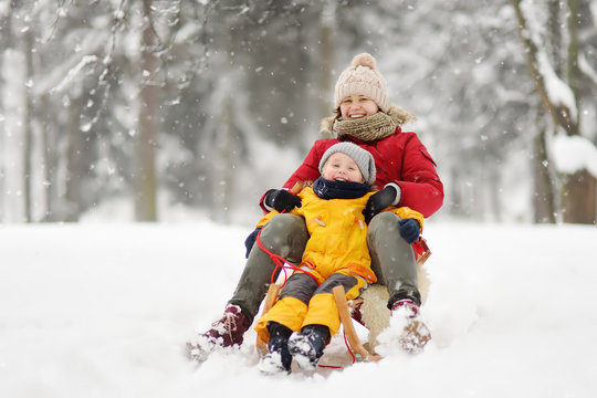 Little boy and mother sliding in the snow