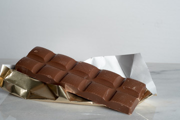 closeup of a chocolate bar with golden wrap paper isolated on white background 