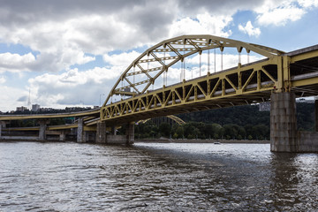 Yellow bridge crossing large river into urban area