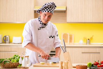 Young professional cook preparing salad at kitchen