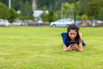 young asian woman lie on your stomach and using smart phone