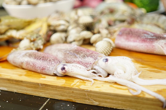 Fresh Seafood background of Crab, Cockles, Squid and Prawn on a chopping board. Food Preparation Concept. Raw Delicious Seafood