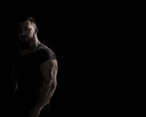 Bodybuilder portrait. Muscular man in a tight-fitting T-shirt. Dramatic portrait in unsaturated...