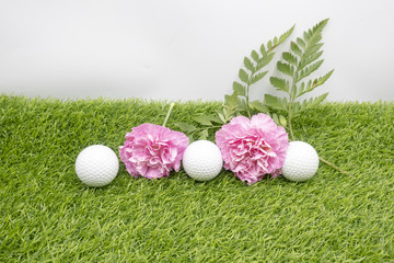 Golf ball with pink carnation on green gras