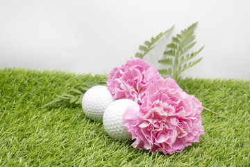 Golf ball with pink carnation on green gras