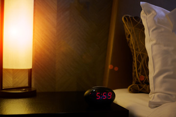 Alarm clock electronic stands on a bedside table near the bed © pavlovski