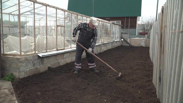 man leveling the ground with a rake