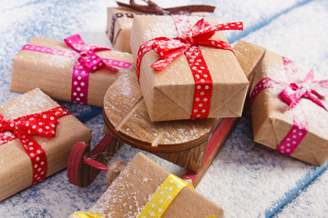 Wooden sled and wrapped gifts for Christmas lying on snowy boards
