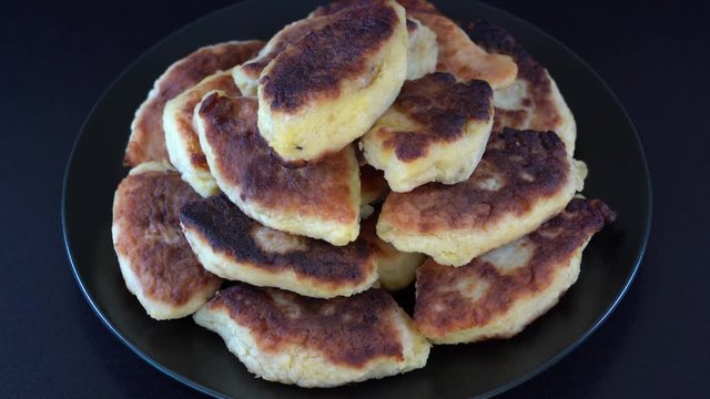 Potato cakes, ukrainian name potato zrazy, stuffed mushrooms or meat or cheese with herbs cream are fried in vegetable oil on black background, close up, rotates. Traditional Ukrainian cuisine