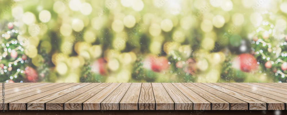Fototapete Empty brown wooden table top with abstract green blur christmas tree and snow fall background with bokeh light,Holiday backdrop,Mock up banner for display or montage of product.