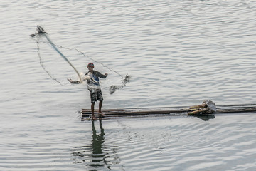 Fischer auf einem See in Indonesien wirft sein Netz aus