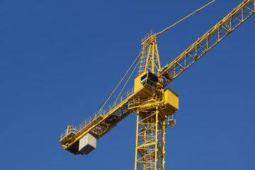 Fragment of the building elevating crane against the blue sky in a fair weather