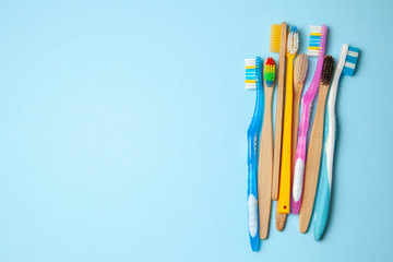 Many colored toothbrushes on blue background. How to choose toothbrush