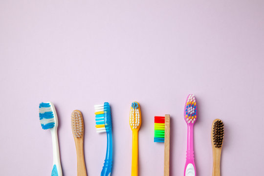 Many colored toothbrushes on purple background. How to choose toothbrush