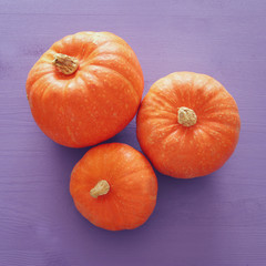 Halloween holiday minimal top view image of pumpkin over purple wooden background.