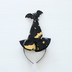 Fototapeta premium Halloween holiday minimal top view image of witch hat over white wooden background.