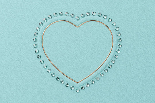Heart shaped frame of diamonds and yellow gold on tiffany blue background. 3D rendering