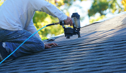 handyman using nail gun to install shingle to repair roof - obrazy, fototapety, plakaty
