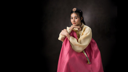 Beautiful Korean girl in Hanbok dress. Looks adorable and elegant. standing front of black background.