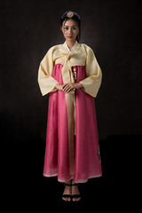 Beautiful Korean girl in Hanbok dress. Looks adorable and elegant. standing front of black background.