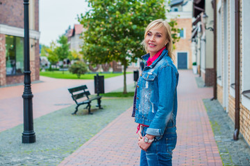 Portrait of attractive mature woman in casual style walk at city at autumn day and thinking about something. Life of women after 35- 40 years 