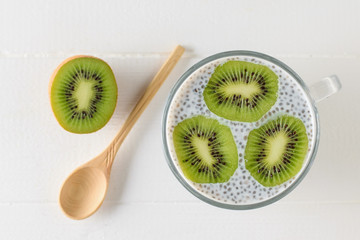 A mug of black Chia seed pudding and wooden spoon on a white table. The view from the top. Flat lay.