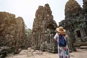 Young woman traveler visiting in Bayon temple at Angkor Wat complex, Khmer architecture heritage in Siem Reap, Cambodia