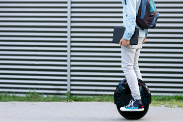 Modern young adult male businessman student freelancer with backpack and laptop riding on ecological electric transport futuristic eco electric unicycle scooter, balancing electric wheel. Eco planet. - Powered by Adobe