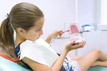 Girl 10 years old in dental chair, with tooth brush. Medicine, dentistry and healthcare concept
