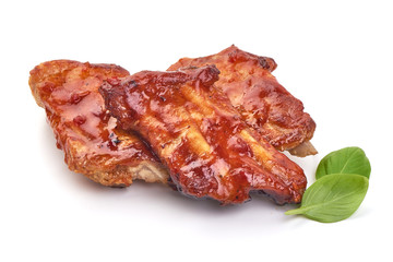 Delicious spicy marinated ribs in a bbq or tomato sauce with basil leaves, isolated on a white background. Close-up.