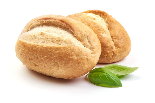 Freshly baked crispy bread rolls with basil leaves, close-up, isolated on a white background.