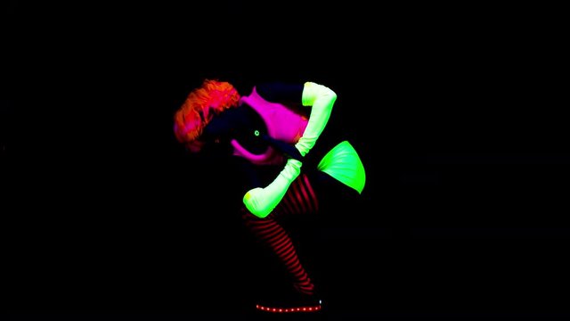 amazing female yoga instructor moving between poses wearing fluorescent clothing under UV black light