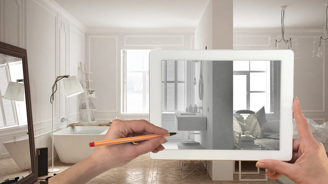 Hands holding and drawing on tablet showing total white bedroom and bathroom interior sketch. Real finished minimalist interior in the background, architecture design presentation