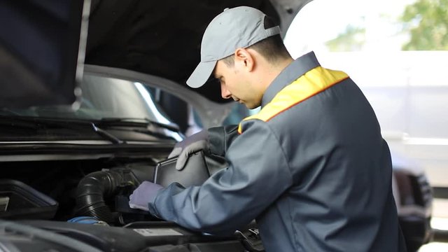 Mechanic pouring oil into a truck engine