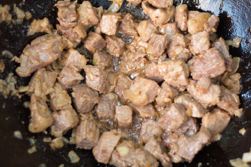 Fry meat for cooking pilaf meat with rice on fire in the cauldron. Recipe