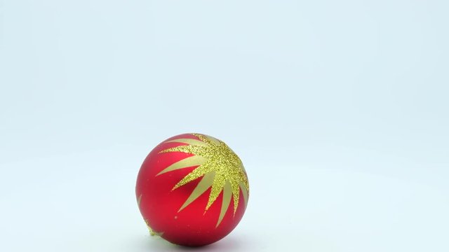 Christmas red ball with golden glittered star rotating on white background.