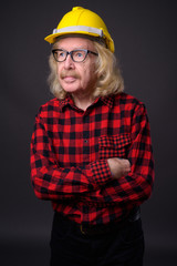 Senior man construction worker against gray background