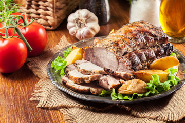 Roasted pork loin with baked potatoes and herbs