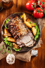 Roasted pork loin with baked potatoes and herbs