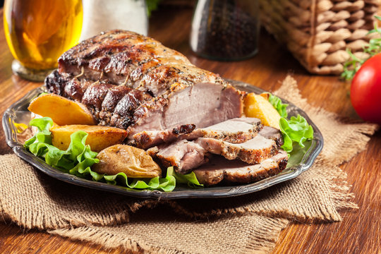 Roasted pork loin with baked potatoes and herbs