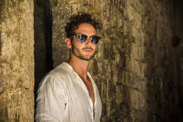 Handsome fit man standing on old brick lane in Italian town. Horizontal outdoors shot