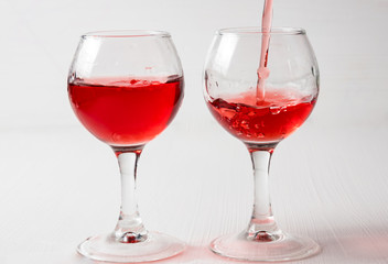 Two glasses with red juice, wine with different splashes