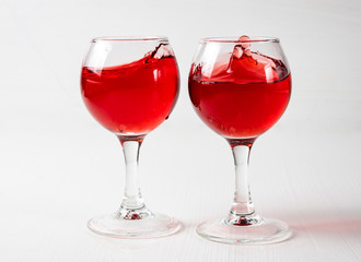 Two glasses with red juice, wine with different splashes