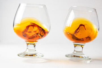 Two glasses for cognac with whiskey with different splashes