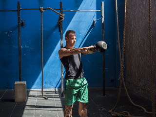 Young man working out with kettlebells in gym, standing