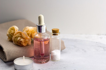 Obraz na płótnie Canvas aroma oil sea salt bottles fresh flowers on towel marble table spa welness concept copy space